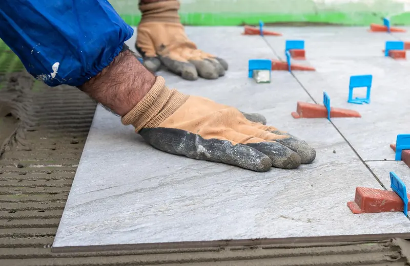 Fliesenleger legt eine großformatige Bodenfliese mit Nivelliersystem