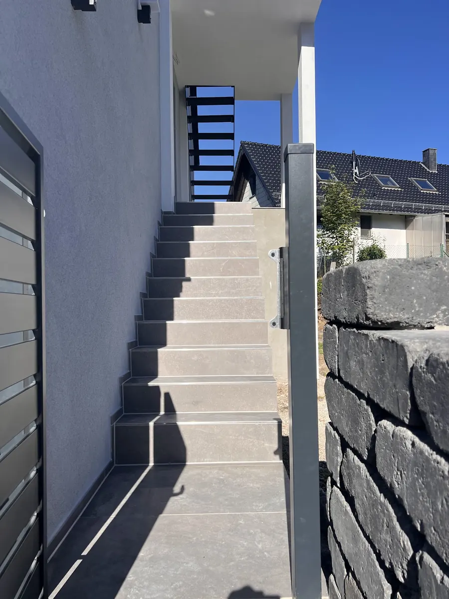 Außentreppe mit Natursteinmauer an einem Wohnhaus
