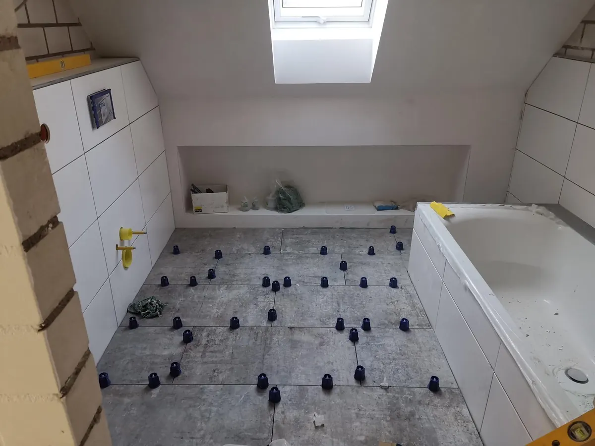 Bodenfliesen im Badezimmer mit Badewanne beim Verlegen