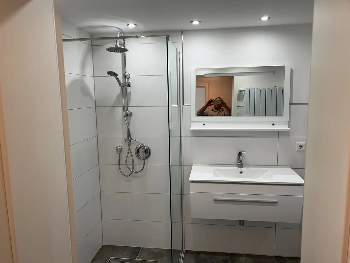Badezimmer mit Glasdusche, Waschtisch und Spiegelschrank