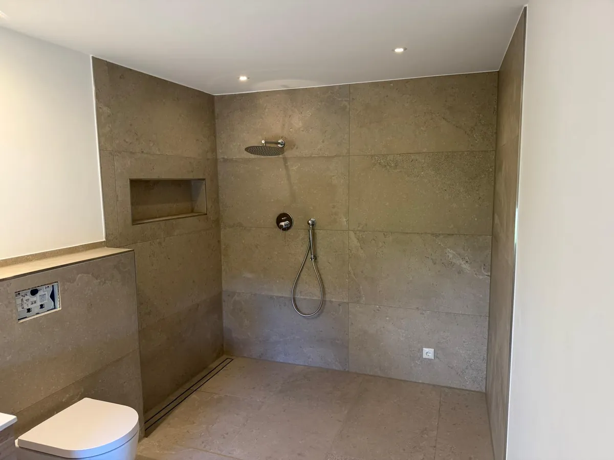 Bodengleiche Walk-in-Dusche mit Regenbrause und Wandnische in Steinoptik