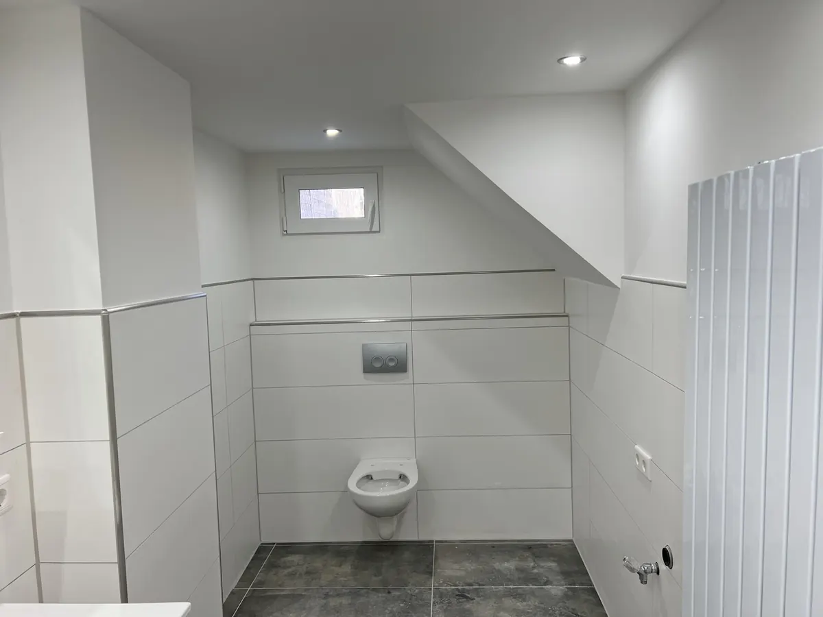 Gäste-WC mit weißen Wandfliesen und Wand-WC