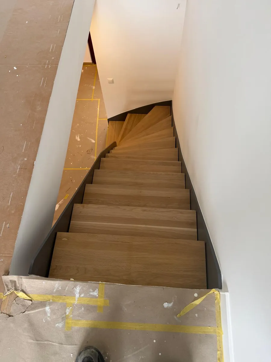 Innentreppe mit Eichenstufen und anthrazitfarbenen Wangen, Baustelle noch abgedeckt